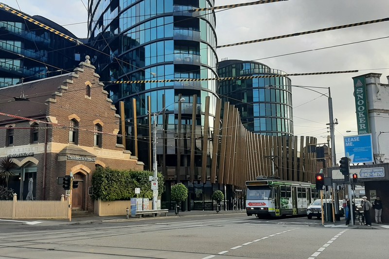 A heritage brick building beside modern architecture and a tram in Camberwell, Melbourne