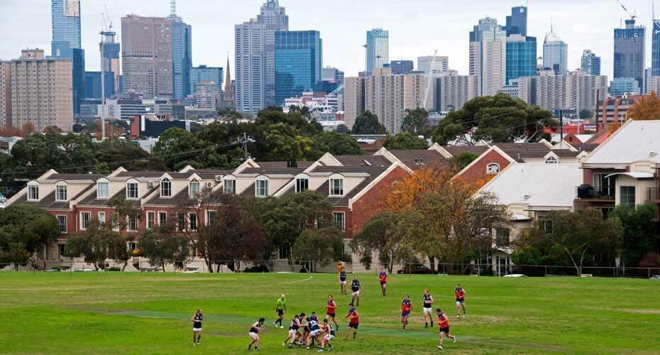 Townhouses and a sports oval in Clifton Hill with the Melbourne city skyline behind
