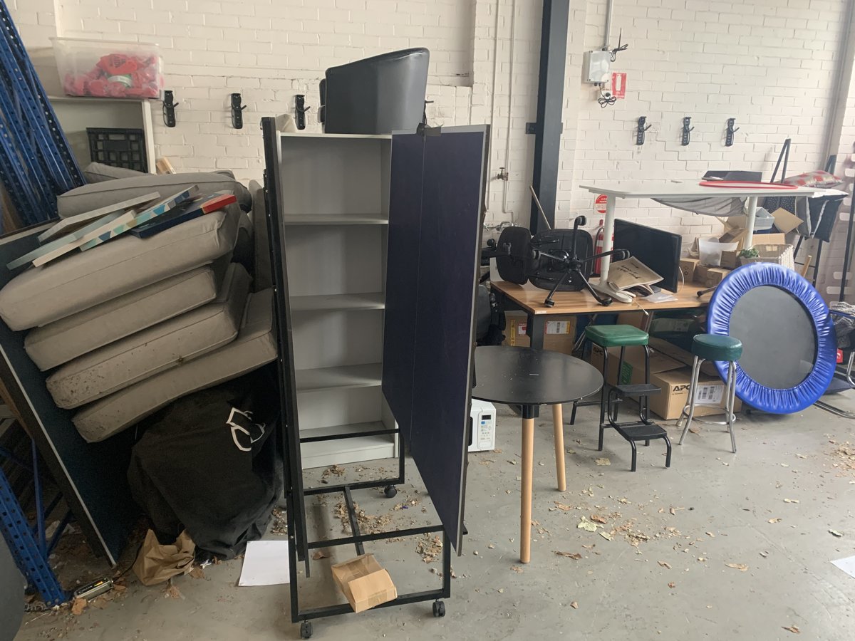 Garage cleanout in progress with old shelving, cushions and furniture stacked for removal