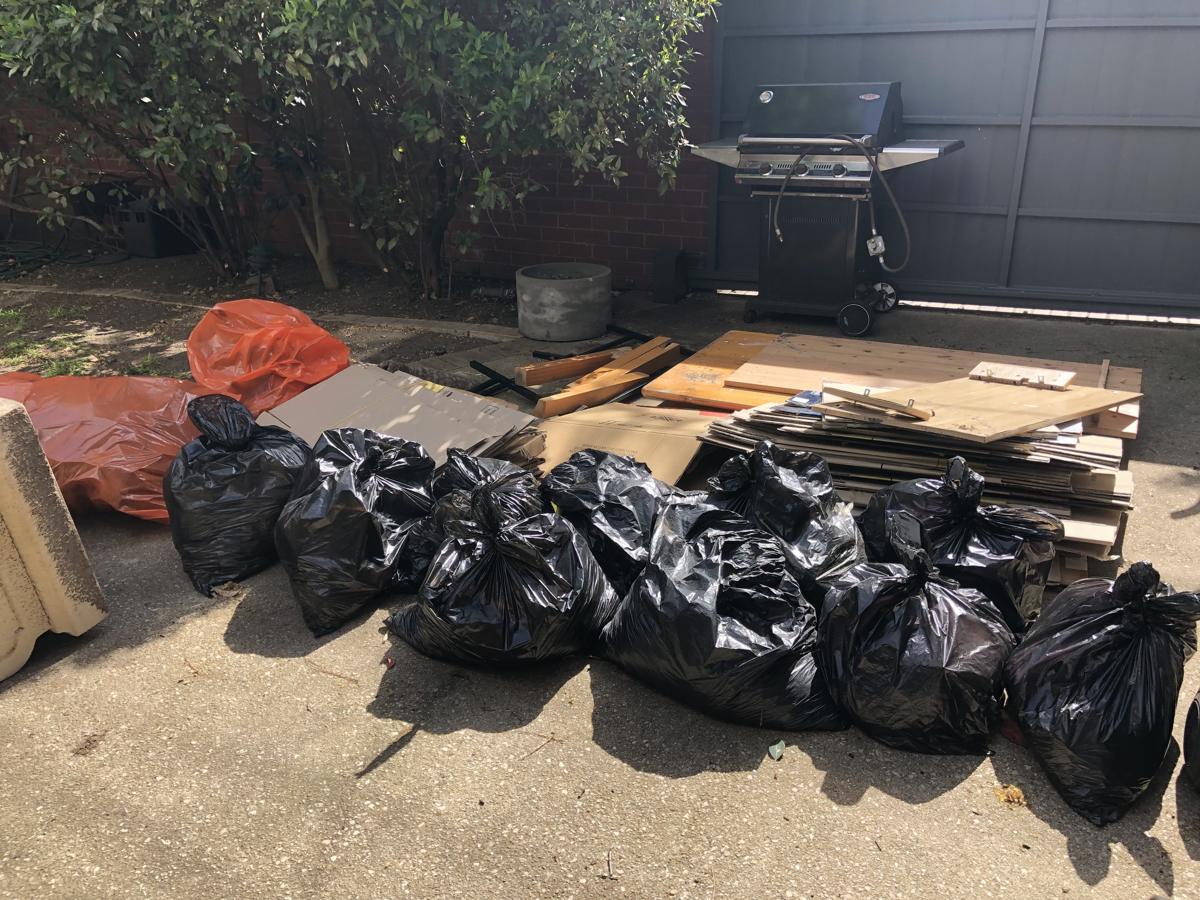 Row of bagged household rubbish and boxes laid out on a Melbourne driveway ready for collection