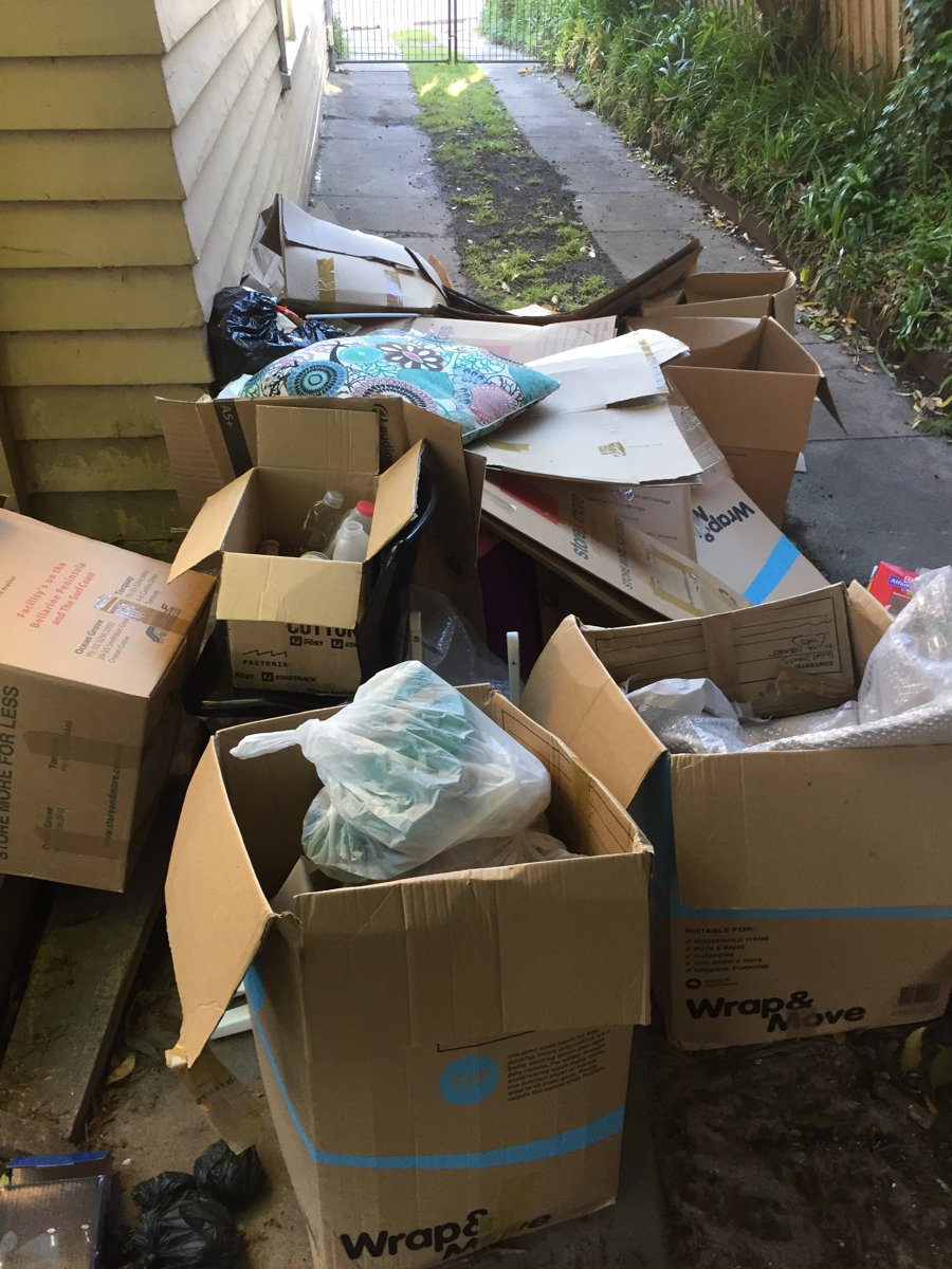 Boxes and bags of household rubbish cleared from a narrow side passage
