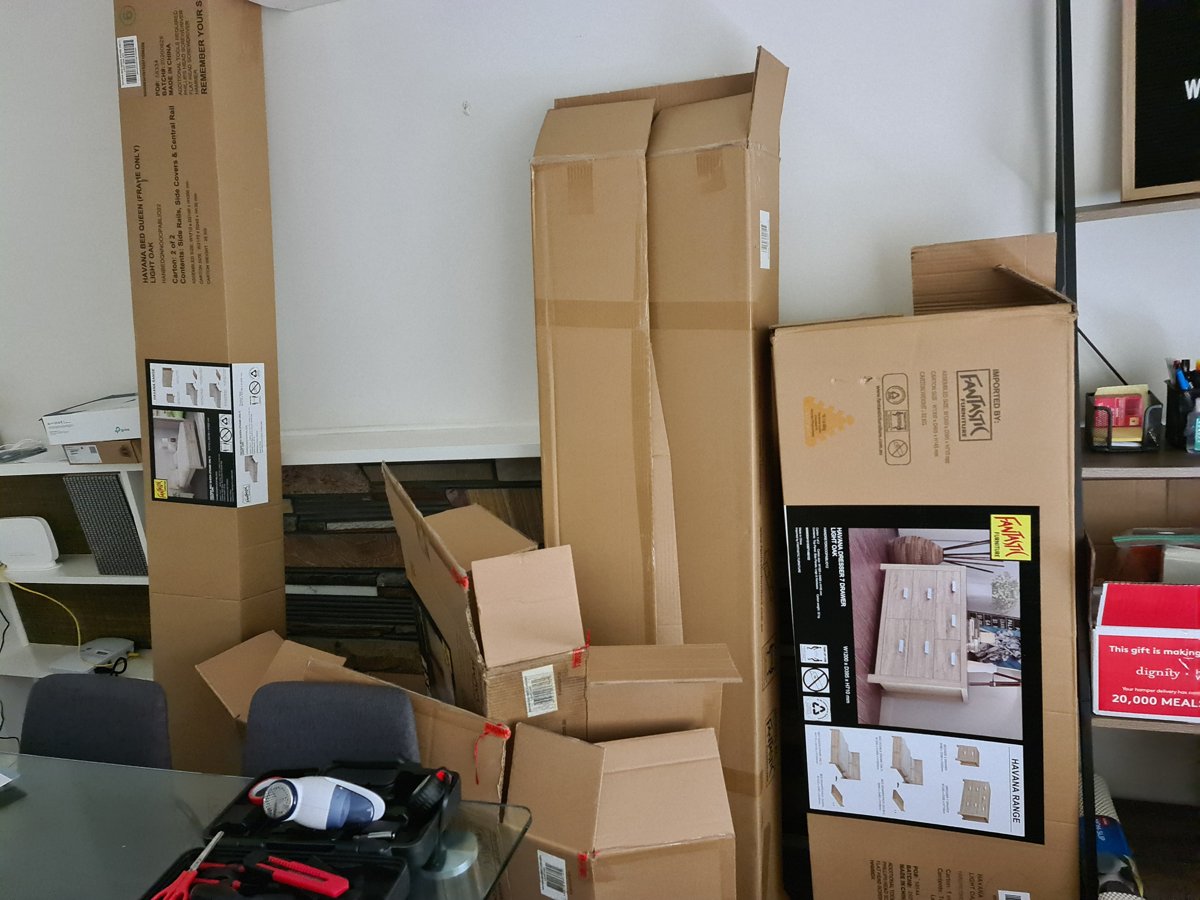 Flat-pack boxes, shelving and an office chair stacked for removal from an office