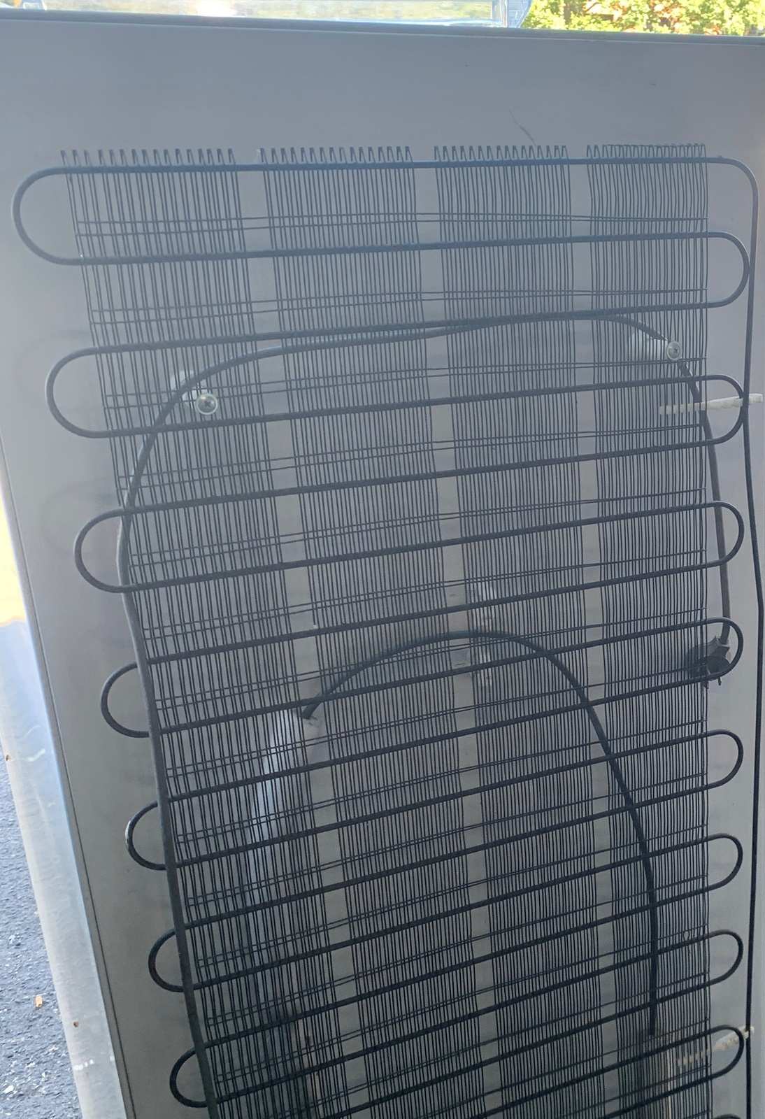 Black condenser coils across the rear panel of an old fridge left on a Melbourne kerb for collection